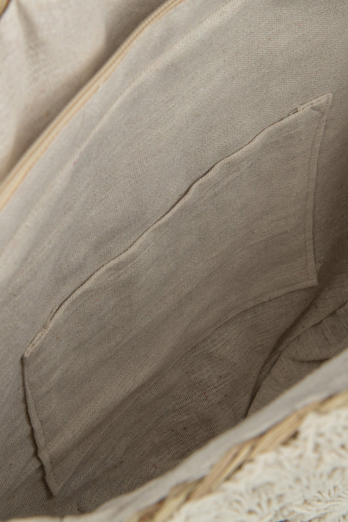 Strandtas met ronde vorm en kwastje van zeegras/kant in natuurlijke/witte kleur.